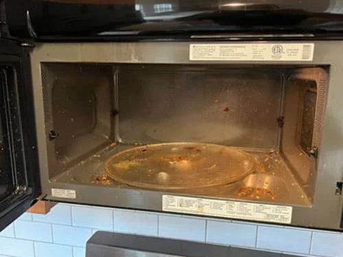Microwave interior greasy and food-splattered before cleaning